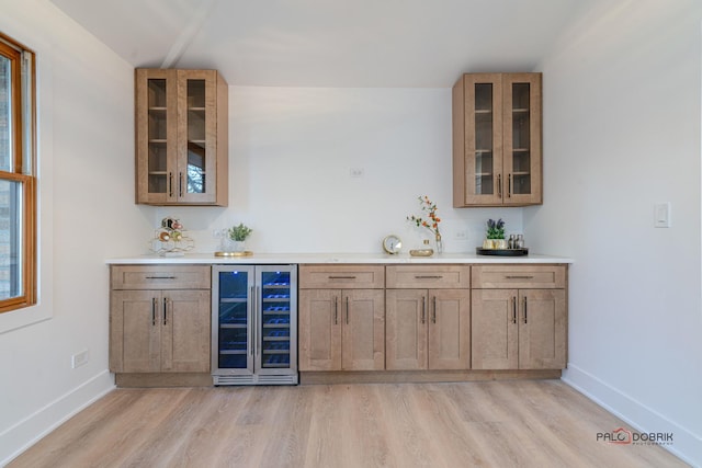 bar with light hardwood / wood-style floors and beverage cooler