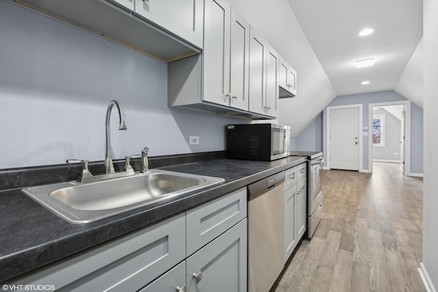 kitchen featuring stainless steel appliances, lofted ceiling, sink, and light wood-type flooring