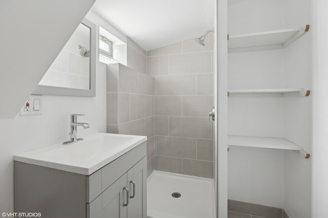 bathroom with vanity, lofted ceiling, and a tile shower