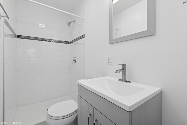 bathroom featuring tiled shower, vanity, and toilet