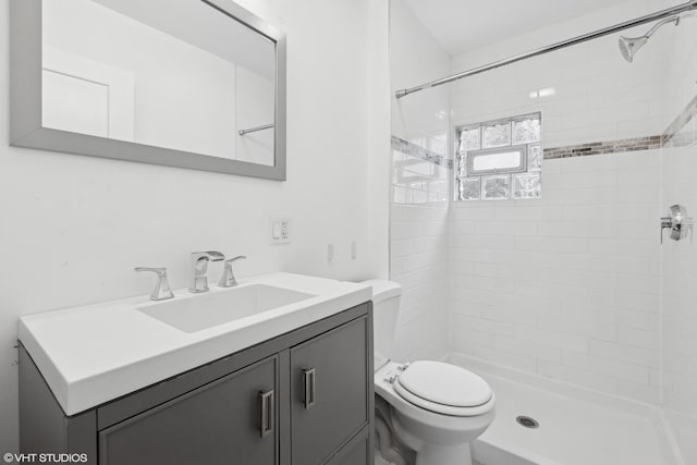 bathroom with vanity, toilet, and tiled shower