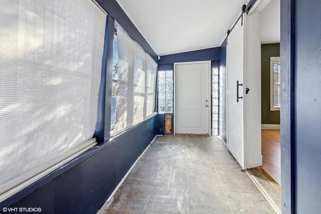 unfurnished sunroom with a barn door and vaulted ceiling