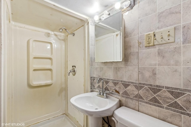 bathroom featuring sink, tile walls, decorative backsplash, walk in shower, and toilet