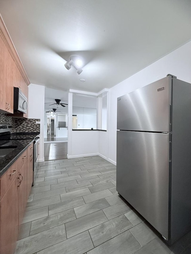 kitchen featuring dark stone countertops, backsplash, ceiling fan, and appliances with stainless steel finishes