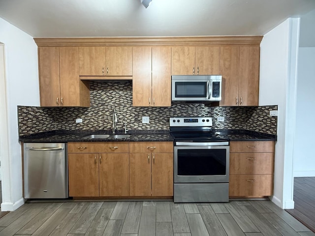 kitchen with tasteful backsplash, stainless steel appliances, sink, and dark stone countertops