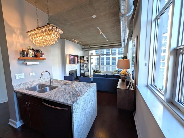 kitchen featuring dark wood-type flooring, sink, hanging light fixtures, black dishwasher, and light stone countertops