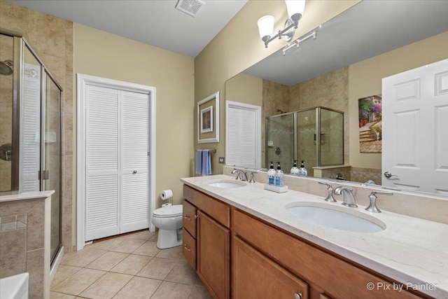 bathroom featuring tile patterned flooring, vanity, toilet, and a shower with shower door