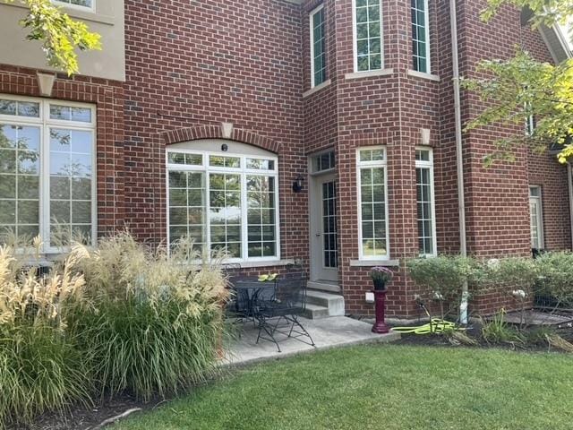 doorway to property featuring a lawn and a patio