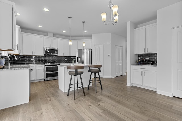 kitchen featuring appliances with stainless steel finishes, pendant lighting, sink, white cabinets, and a center island