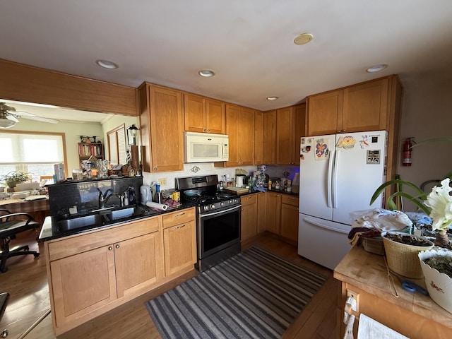 kitchen with hardwood / wood-style floors, sink, ceiling fan, kitchen peninsula, and white appliances