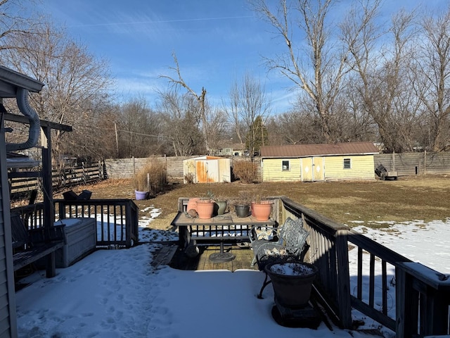 yard layered in snow with a wooden deck and a storage unit