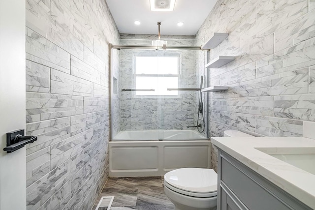 full bathroom with enclosed tub / shower combo, vanity, toilet, and tile walls