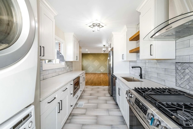 kitchen with stacked washer and dryer, sink, appliances with stainless steel finishes, ventilation hood, and white cabinets