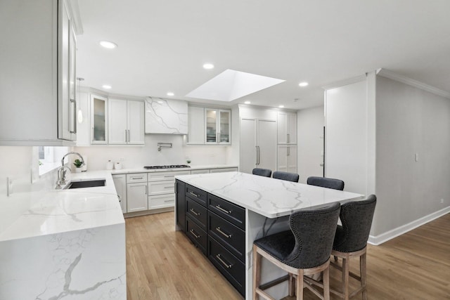 kitchen with a breakfast bar area, a center island, sink, and white cabinets