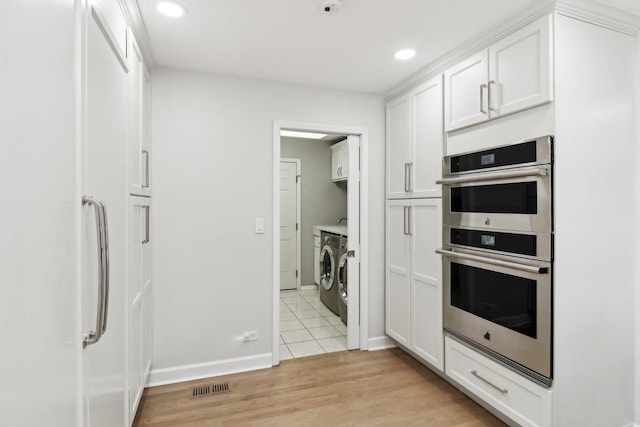 kitchen featuring white cabinetry, double oven, washer and clothes dryer, and light hardwood / wood-style floors