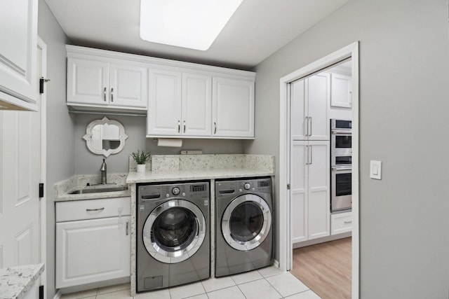 washroom with cabinets, washing machine and clothes dryer, light tile patterned flooring, and sink