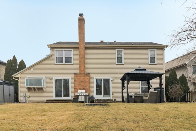 rear view of property featuring a gazebo and a lawn