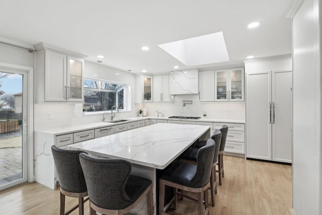 kitchen featuring light stone countertops, a center island, a breakfast bar area, and white cabinets