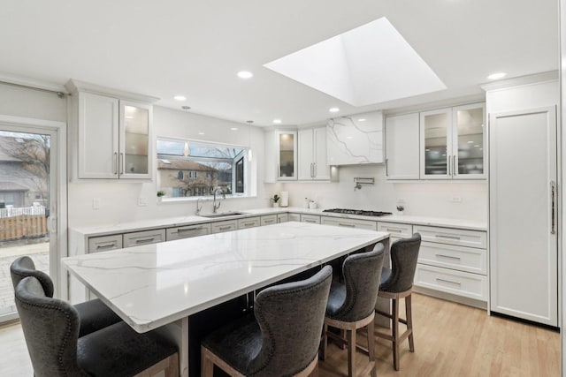 kitchen with a kitchen breakfast bar, sink, a kitchen island, and white cabinets