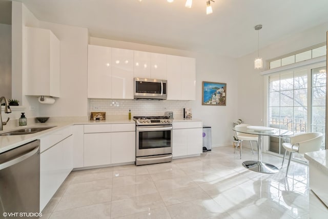 kitchen featuring white cabinetry, sink, decorative backsplash, hanging light fixtures, and stainless steel appliances