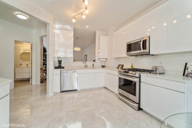 kitchen featuring hanging light fixtures, sink, white cabinets, and appliances with stainless steel finishes