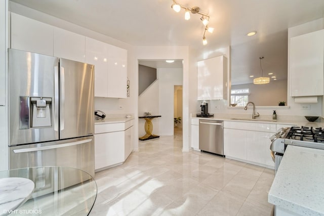 kitchen featuring sink, appliances with stainless steel finishes, pendant lighting, light stone countertops, and white cabinets