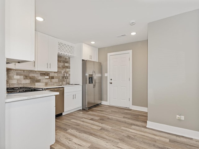 kitchen with sink, decorative backsplash, stainless steel appliances, and white cabinets