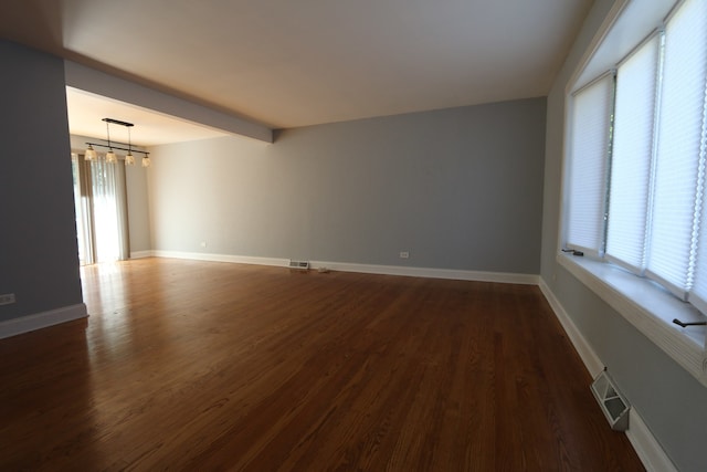 spare room with dark hardwood / wood-style flooring and beamed ceiling