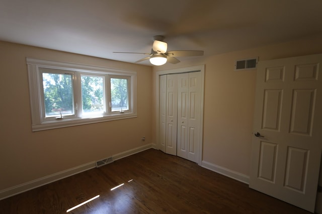 unfurnished bedroom with dark hardwood / wood-style flooring, a closet, and ceiling fan