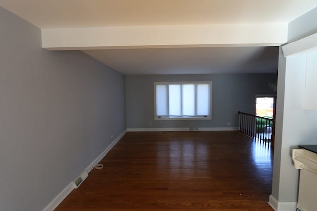 unfurnished room featuring dark hardwood / wood-style flooring and beamed ceiling