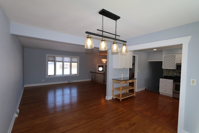 kitchen with pendant lighting, dark wood-type flooring, white cabinets, and appliances with stainless steel finishes