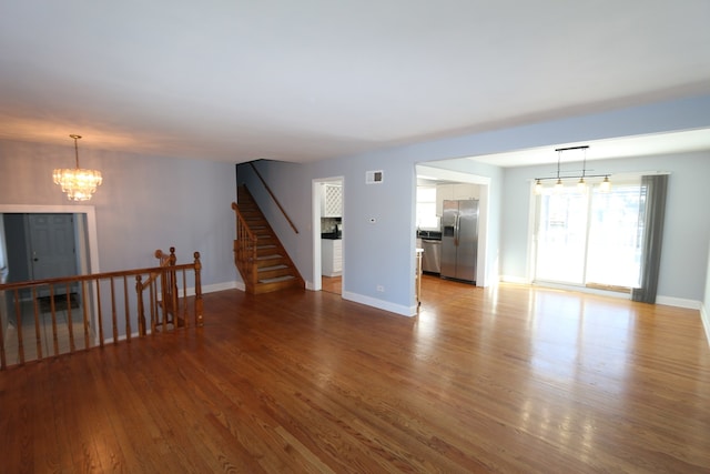 unfurnished room with an inviting chandelier and light hardwood / wood-style floors