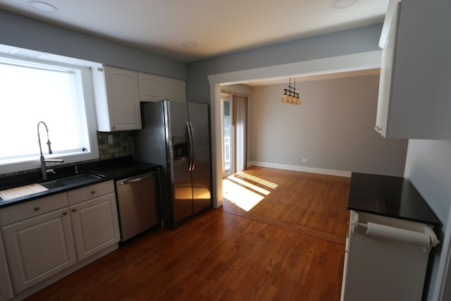 kitchen featuring dark wood-type flooring, white cabinetry, appliances with stainless steel finishes, pendant lighting, and decorative backsplash