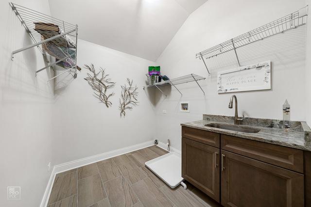 washroom featuring cabinets, hookup for a washing machine, sink, and light hardwood / wood-style flooring