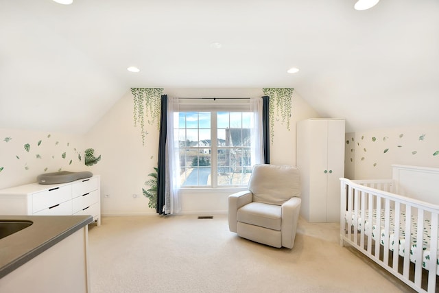 bedroom with a crib, vaulted ceiling, and light colored carpet