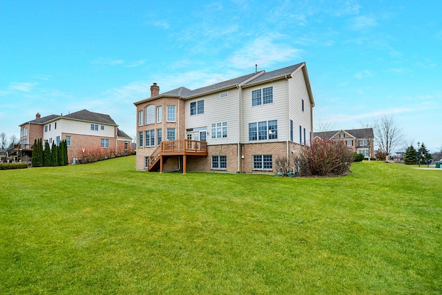 rear view of property with a wooden deck and a lawn