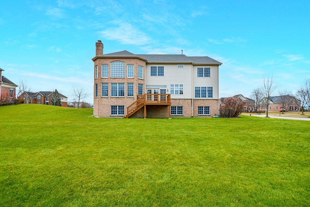 rear view of house with a wooden deck and a lawn