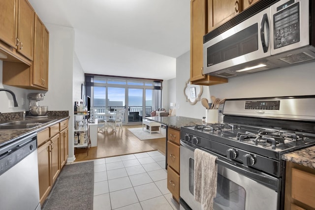 kitchen featuring light tile patterned flooring, appliances with stainless steel finishes, sink, and dark stone counters