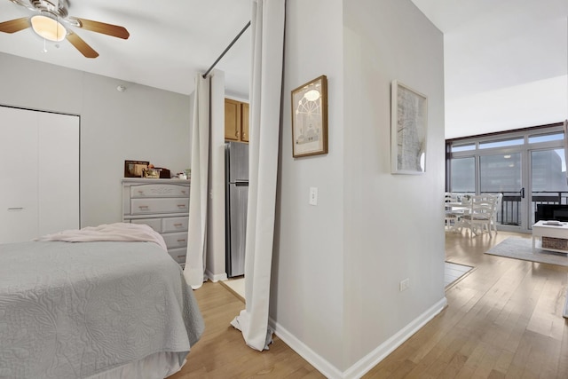 bedroom with access to outside, stainless steel refrigerator, ceiling fan, and light wood-type flooring