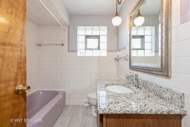 full bathroom featuring plenty of natural light, toilet, tile walls, and vanity