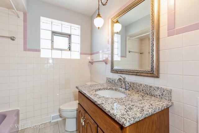 bathroom featuring vanity, tile walls, and toilet