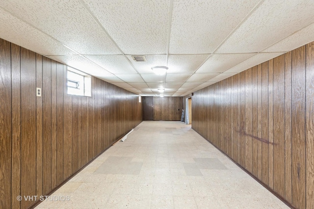 corridor with a paneled ceiling and wood walls