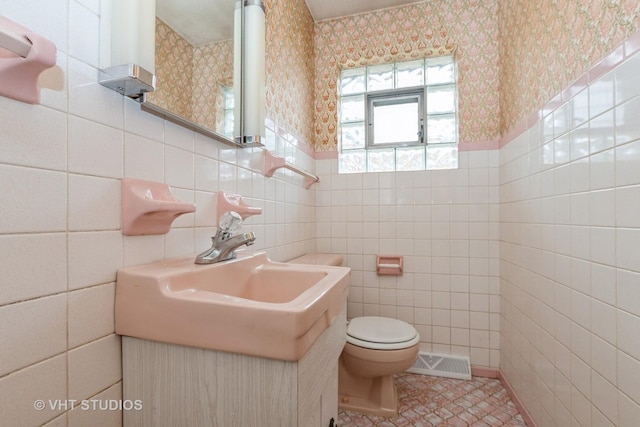 bathroom with vanity, toilet, tile patterned flooring, and tile walls