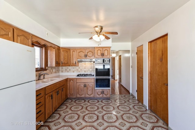 kitchen with sink, backsplash, white fridge, stainless steel gas cooktop, and ceiling fan