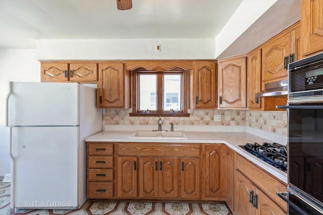 kitchen featuring tasteful backsplash, black gas cooktop, sink, and white fridge