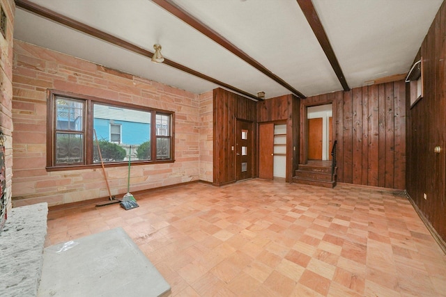 interior space featuring beamed ceiling and wooden walls