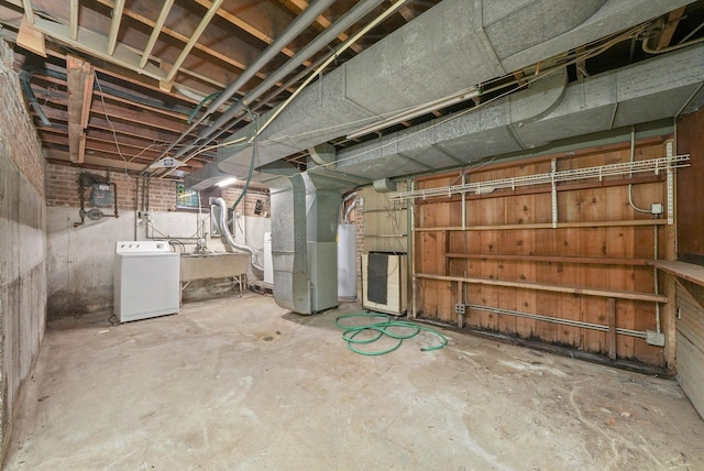 basement featuring washer / clothes dryer, gas water heater, sink, and heating unit