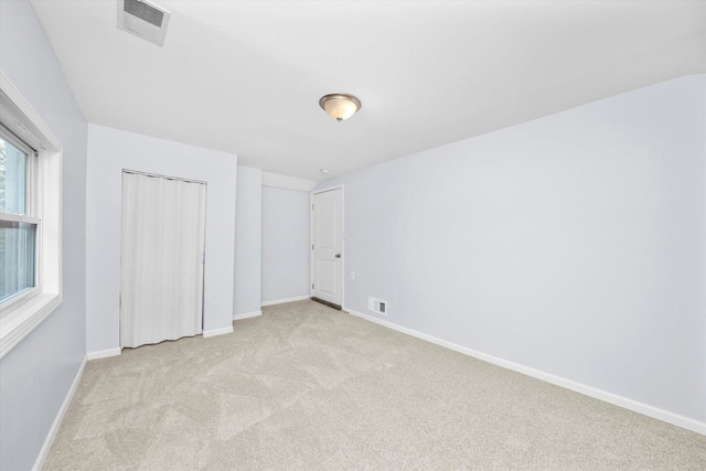 unfurnished bedroom featuring light colored carpet and a closet