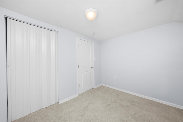 unfurnished bedroom with lofted ceiling, light carpet, and a closet