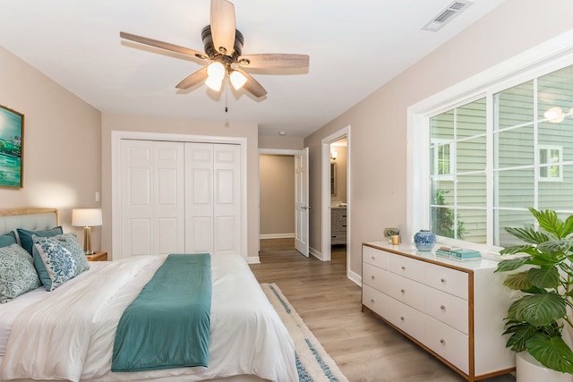 bedroom with ensuite bath, a closet, ceiling fan, and light wood-type flooring